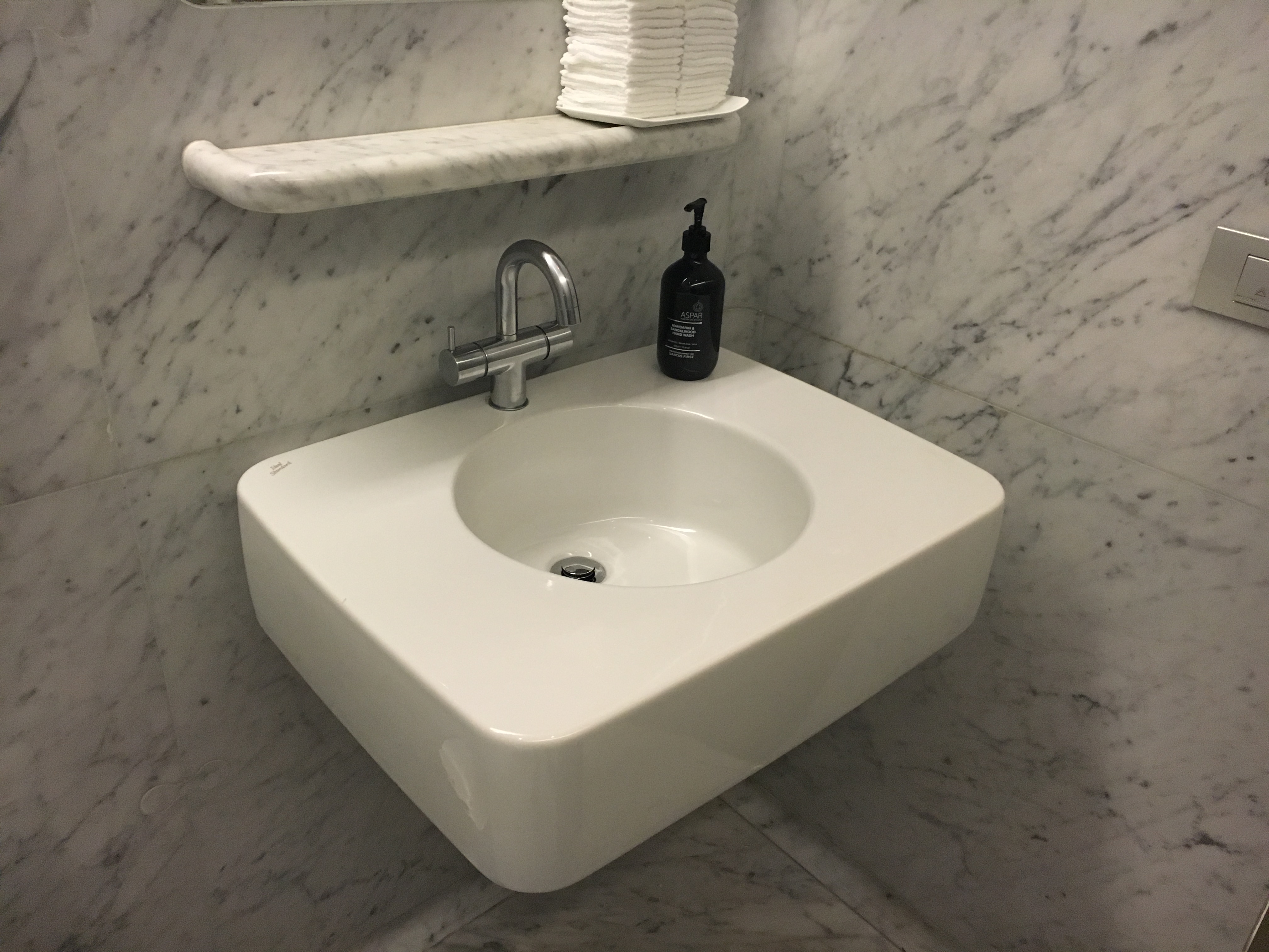 a sink with a soap dispenser and a shelf