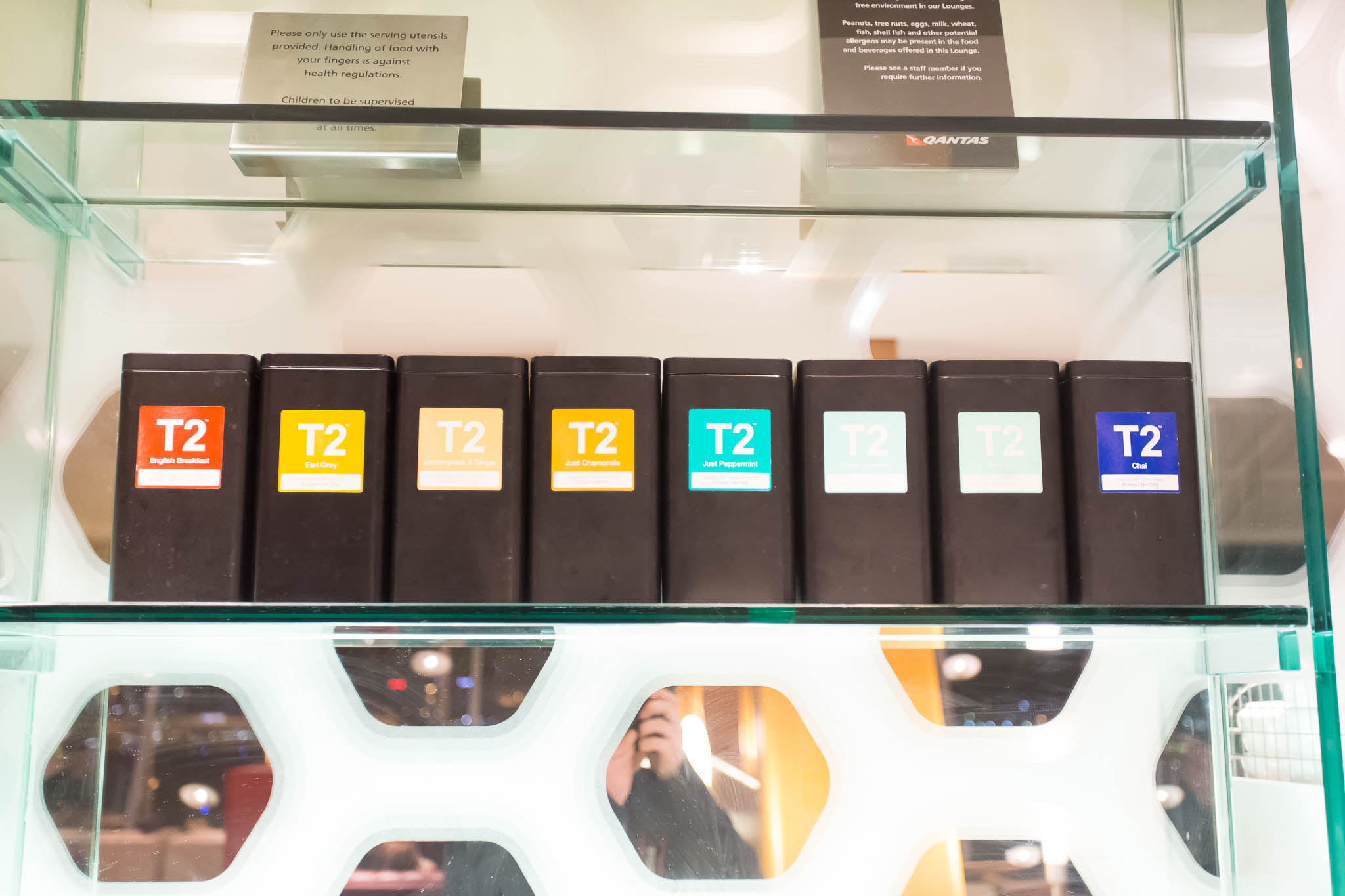 a row of black boxes with colorful labels on a glass shelf